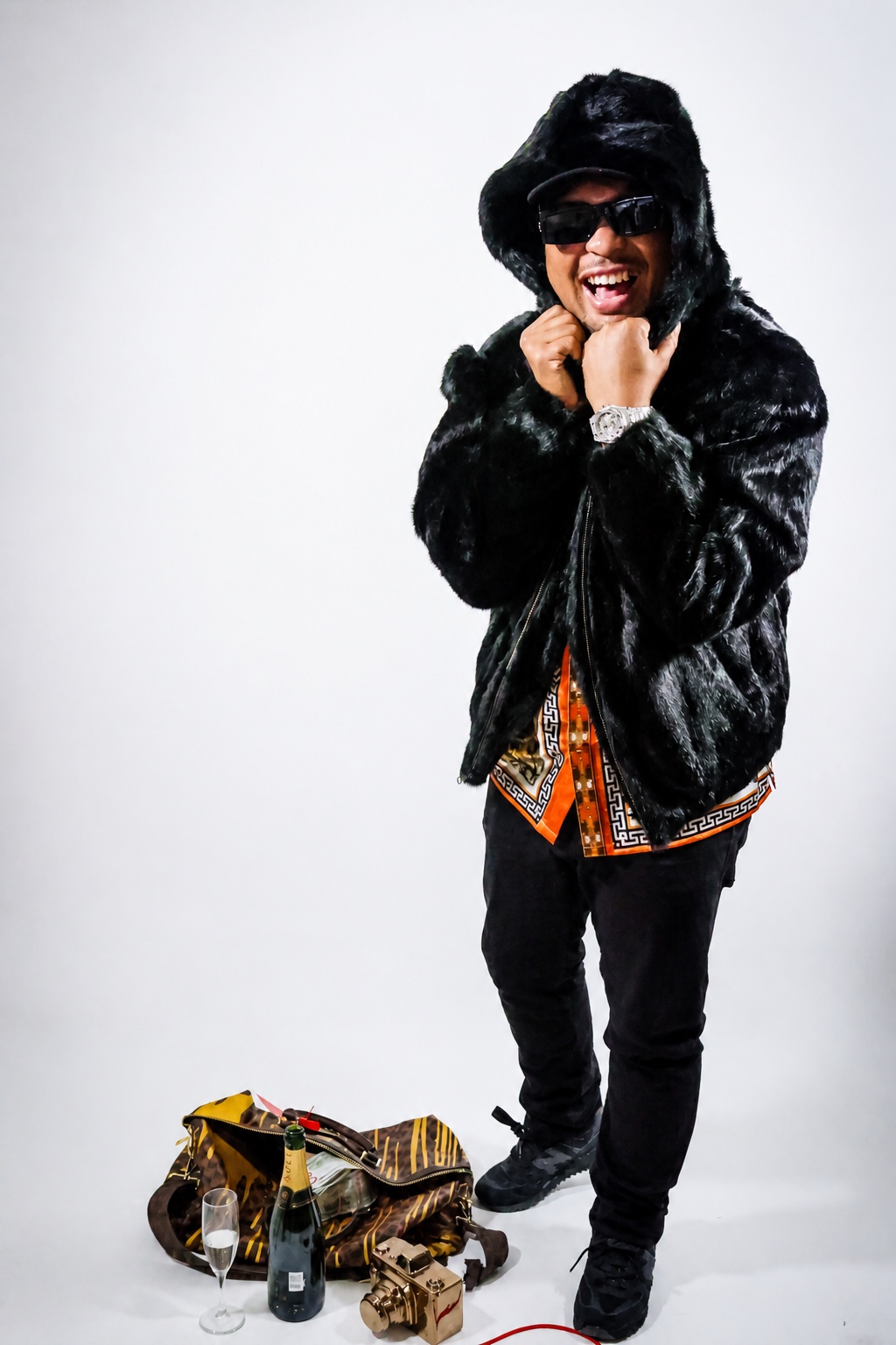 Mackie Fresh wearing a black coat and sunglasses in a studio portrait
